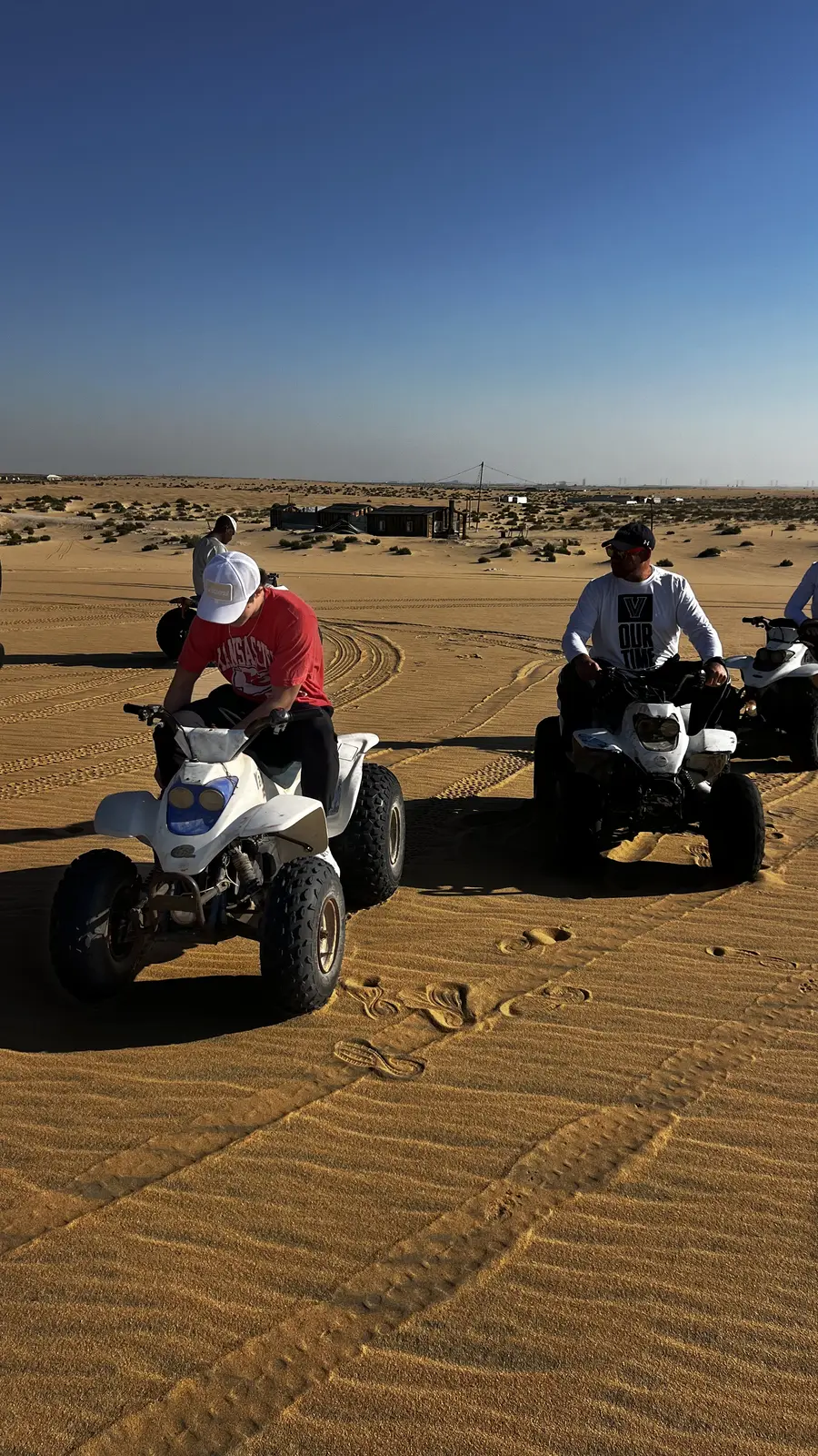 Group riding quad bikes across the golden desert dunes